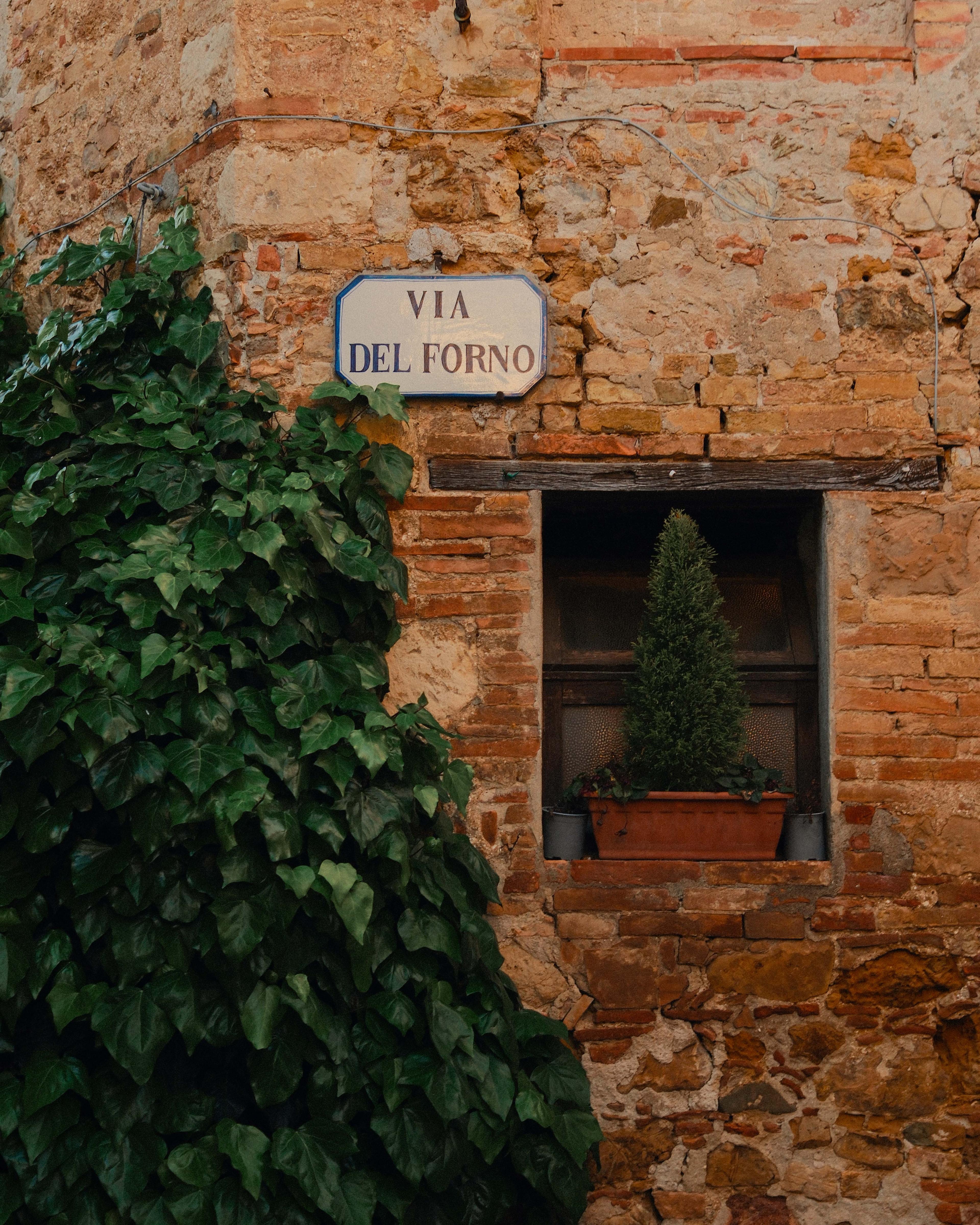 A Via del Forno street sign set into an old brick wall.